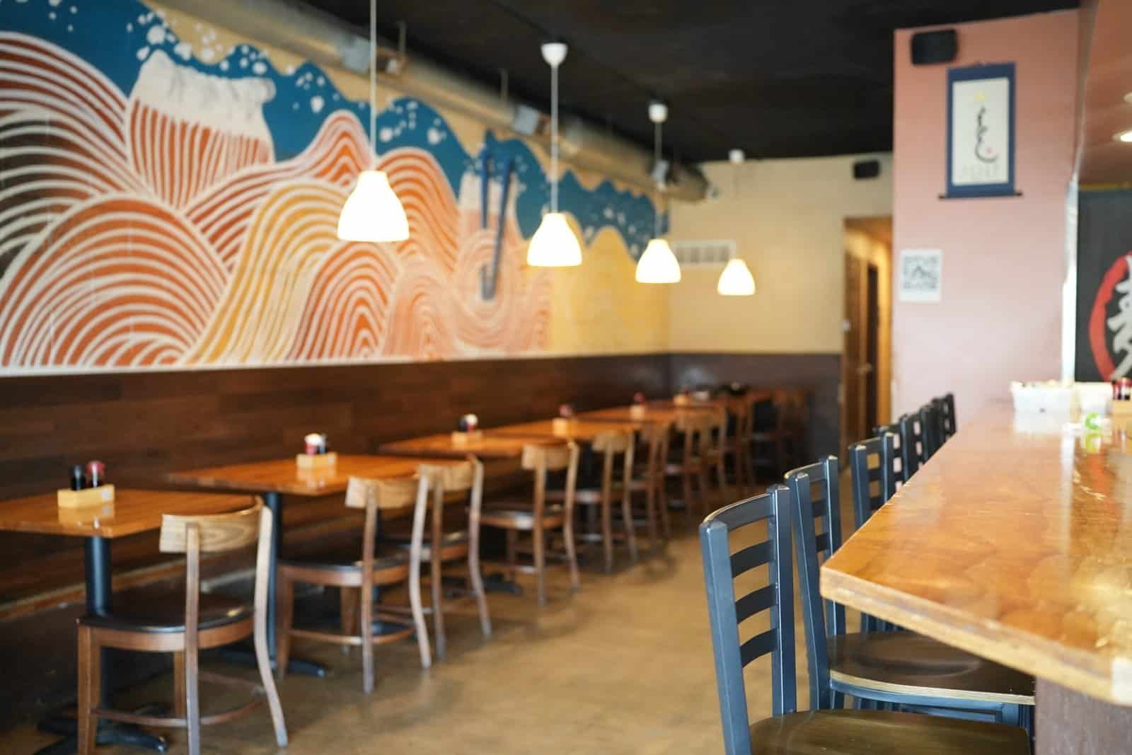 Modern Japanese ramen restaurant interior with warm lighting, wooden accents, and casual seating